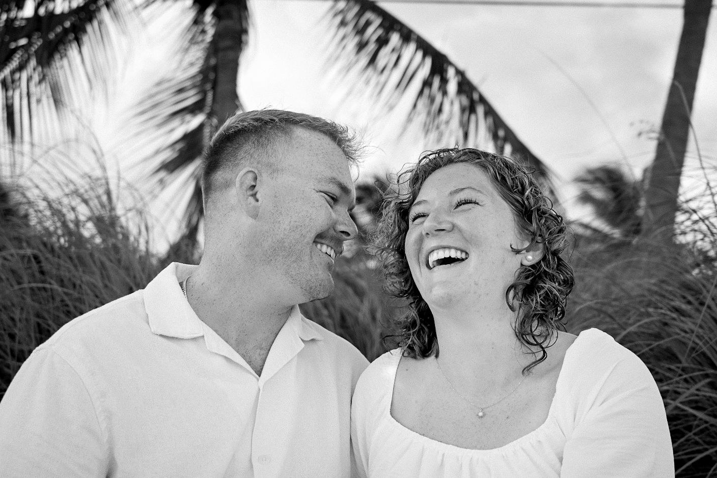 Black and white candid portrait of an engaged couple laughing