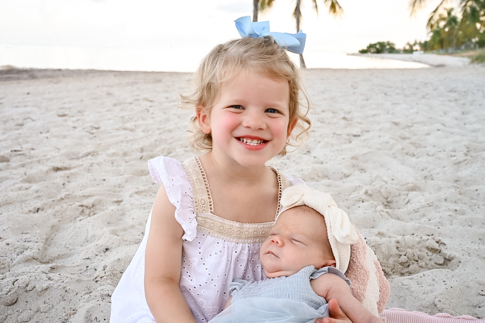 Older sister holding newborn on the beach